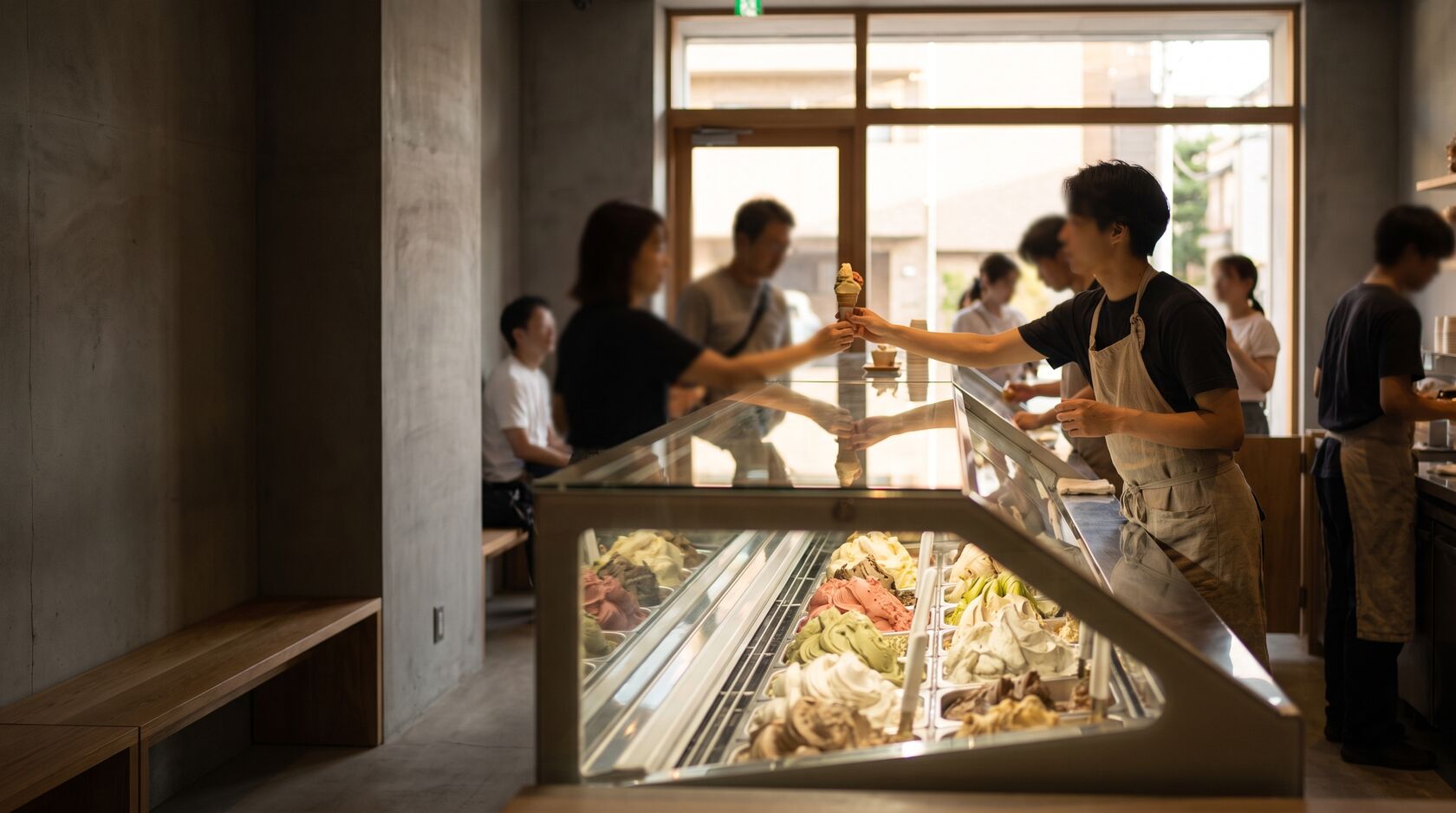 Gelateria artigianale con il banco dei gusti e un cono servito al cliente